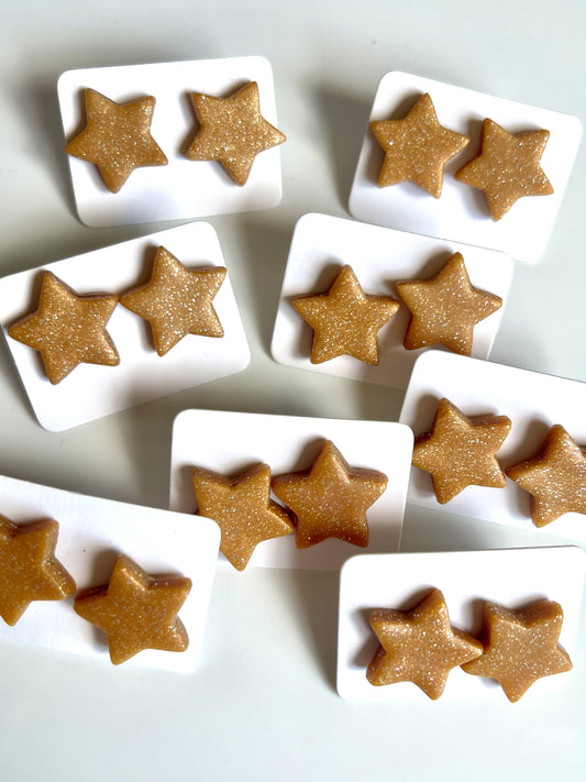 Multiple cards present pairs of Gold Star Polymer Clay Stud Earrings by silverstar.nz, each with star shapes in a glittery golden hue. The stars are arranged neatly on white holders and scattered across a white surface.