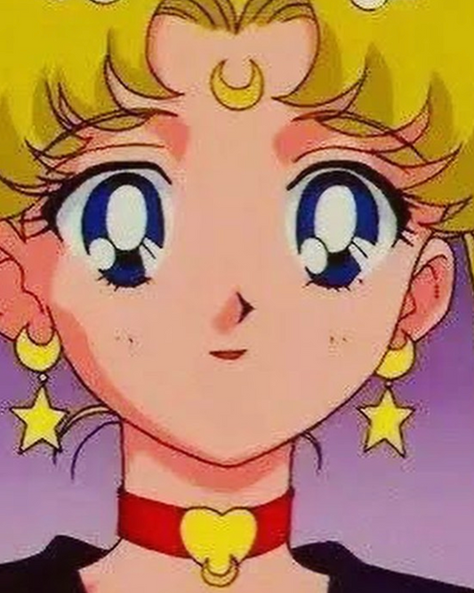 This handmade anime character features large blue eyes, a crescent moon on her forehead, star-shaped polymer clay earrings by silverstar.nz, and a choker with a heart. Her blonde buns are accentuated by a purple gradient backdrop.