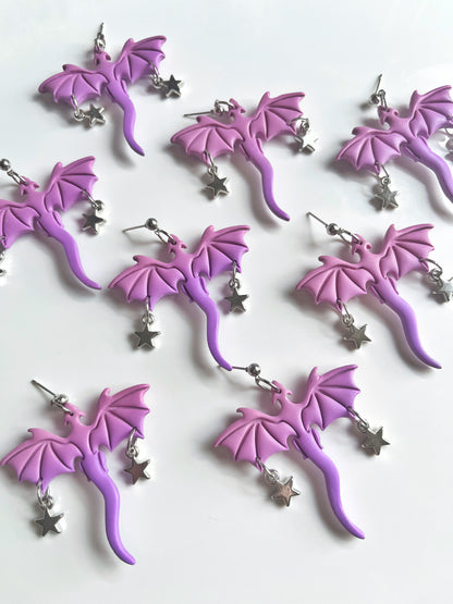 Purple Dragon Polymer Clay Earrings by silverstar.nz are artfully crafted in a dragon shape with star charms. Displayed on a white background, these unique earrings feature detailed wings and tails, showcasing the glossy finish and craftsmanship of handmade jewelry.