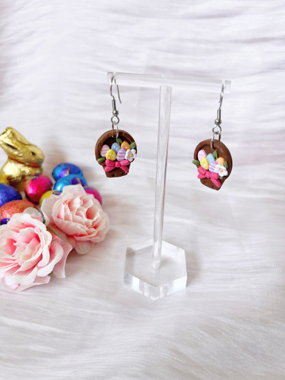 These Egg Basket Polymer Clay Earrings by silverstar.nz showcase a distinctive mini wicker basket design with pastel flowers and eggs. Complemented by pink roses and colorful Easter eggs on a white fabric, theyre the embodiment of charming handmade earrings with a gold-tone bunny.